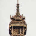 People on the top of the Eiffel Tower as seen from the Quai Branly Museum